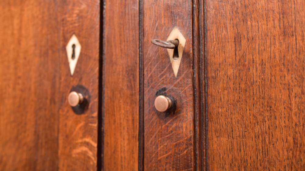 A two-tiered nineteenth-century oak court cupboard featuring panelled doors, drop handles on two upper drawers, and turned finials. View XII