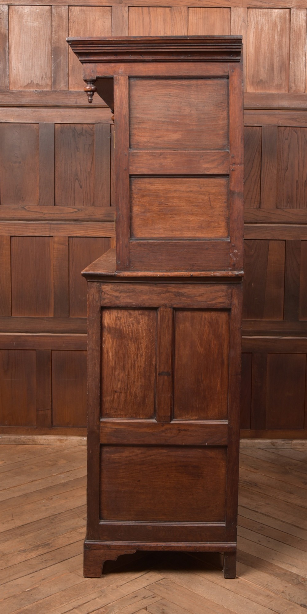 A two-tiered nineteenth-century oak court cupboard featuring panelled doors, drop handles on two upper drawers, and turned finials. View XIII