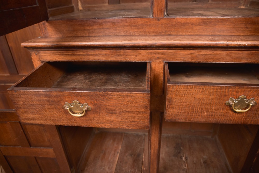 A two-tiered nineteenth-century oak court cupboard featuring panelled doors, drop handles on two upper drawers, and turned finials. View XVIII