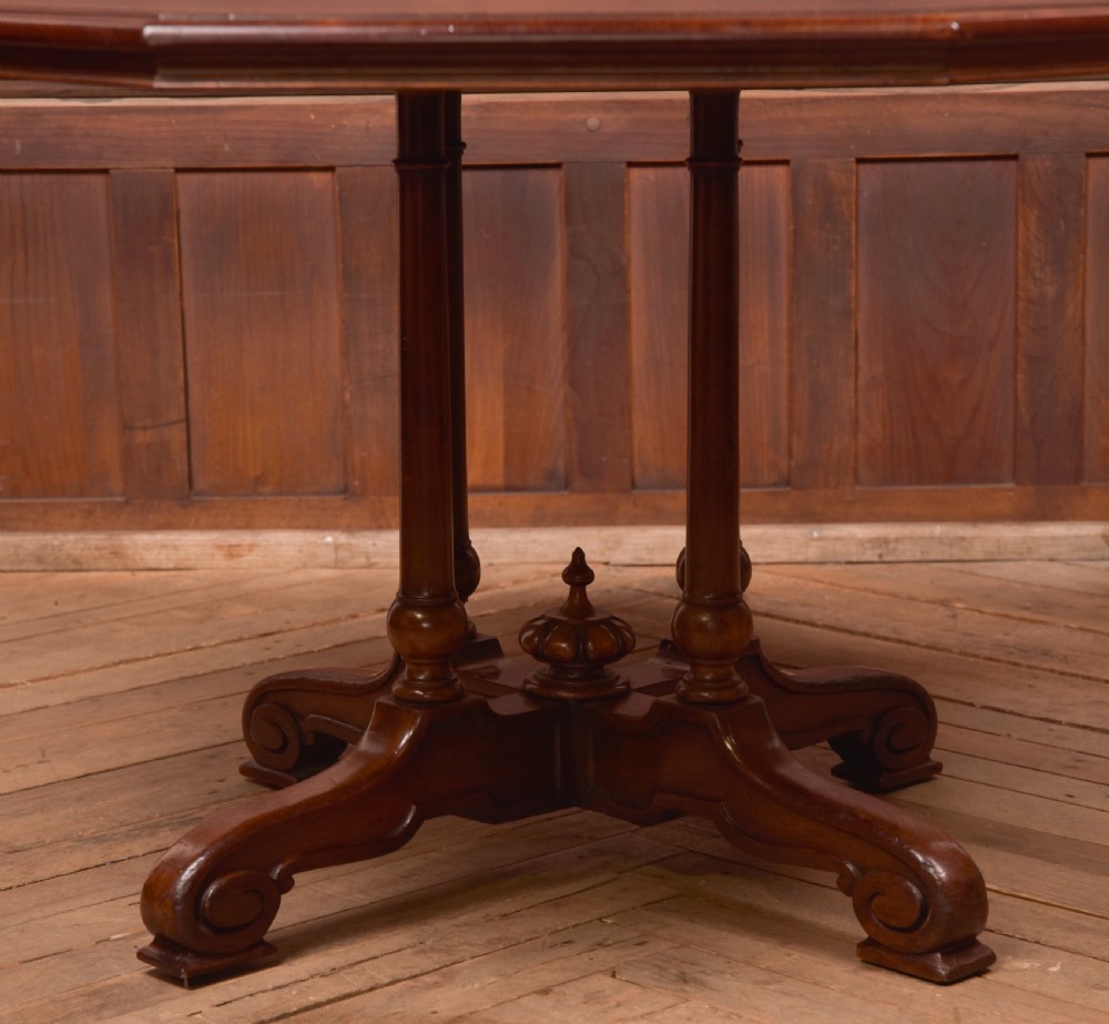 A Victorian octagonal mahogany centre table with a brown leather-inset top, four turned support columns, and a quadruped base with scroll feet. View V