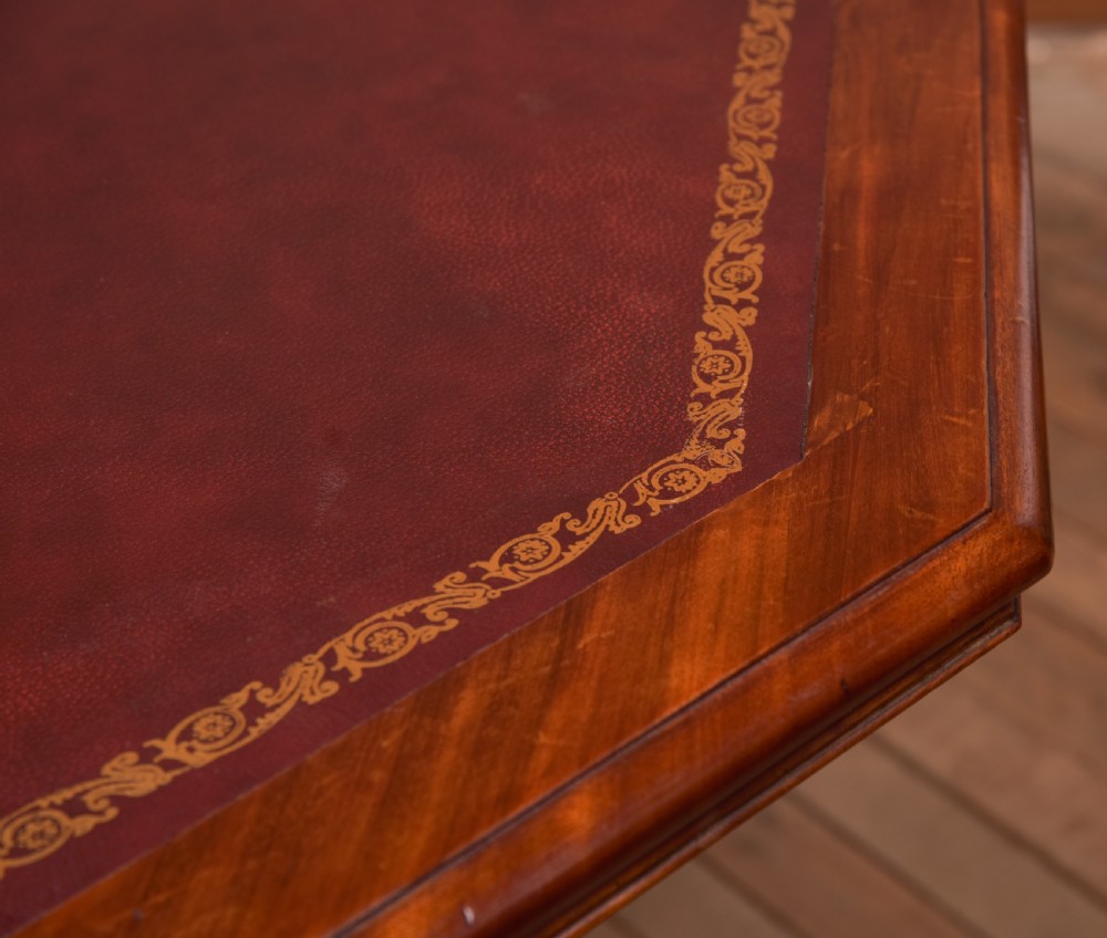 A Victorian octagonal mahogany centre table with a brown leather-inset top, four turned support columns, and a quadruped base with scroll feet. View VII