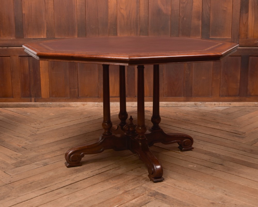 A Victorian octagonal mahogany centre table with a brown leather-inset top, four turned support columns, and a quadruped base with scroll feet. View IX