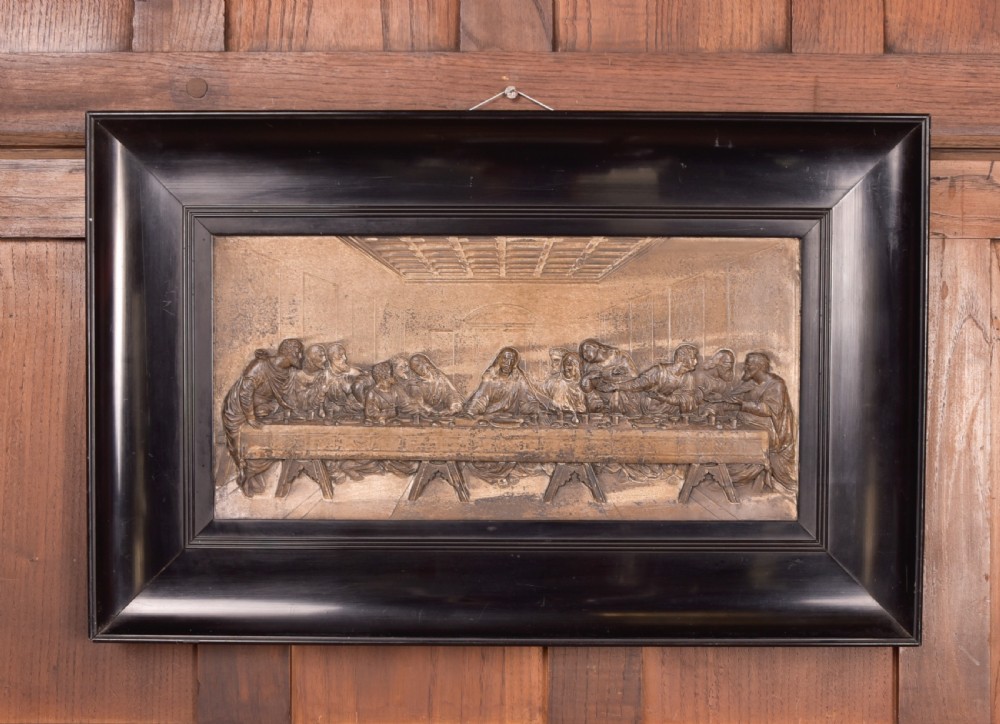 A 19th-century cast metal high-relief plaque depicting The Last Supper mounted inside a deep, black ebonised wooden frame.