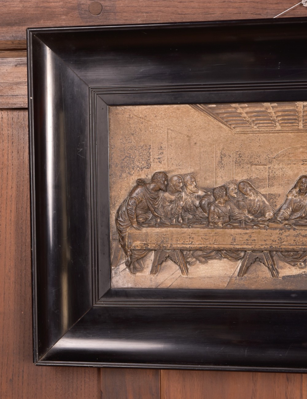 A 19th-century cast metal high-relief plaque depicting The Last Supper mounted inside a deep, black ebonised wooden frame. View IV