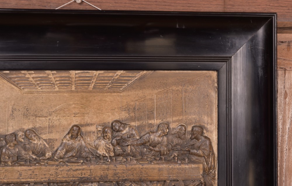A 19th-century cast metal high-relief plaque depicting The Last Supper mounted inside a deep, black ebonised wooden frame. View VII