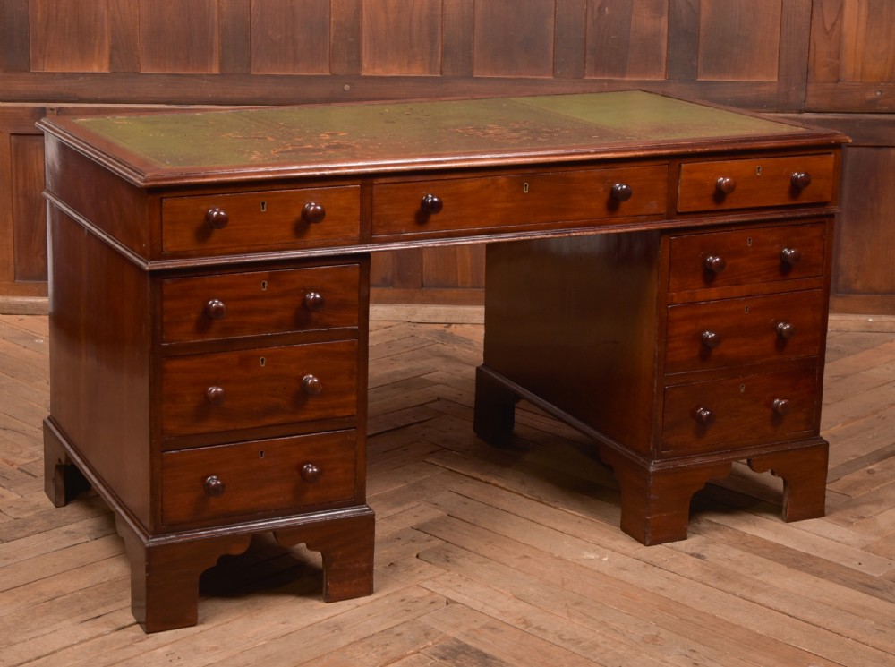 A Victorian mahogany pedestal desk with a green inset leather writing surface, multiple drawers fitted with turned wooden handles, and pedestal bases with bracket feet. View II