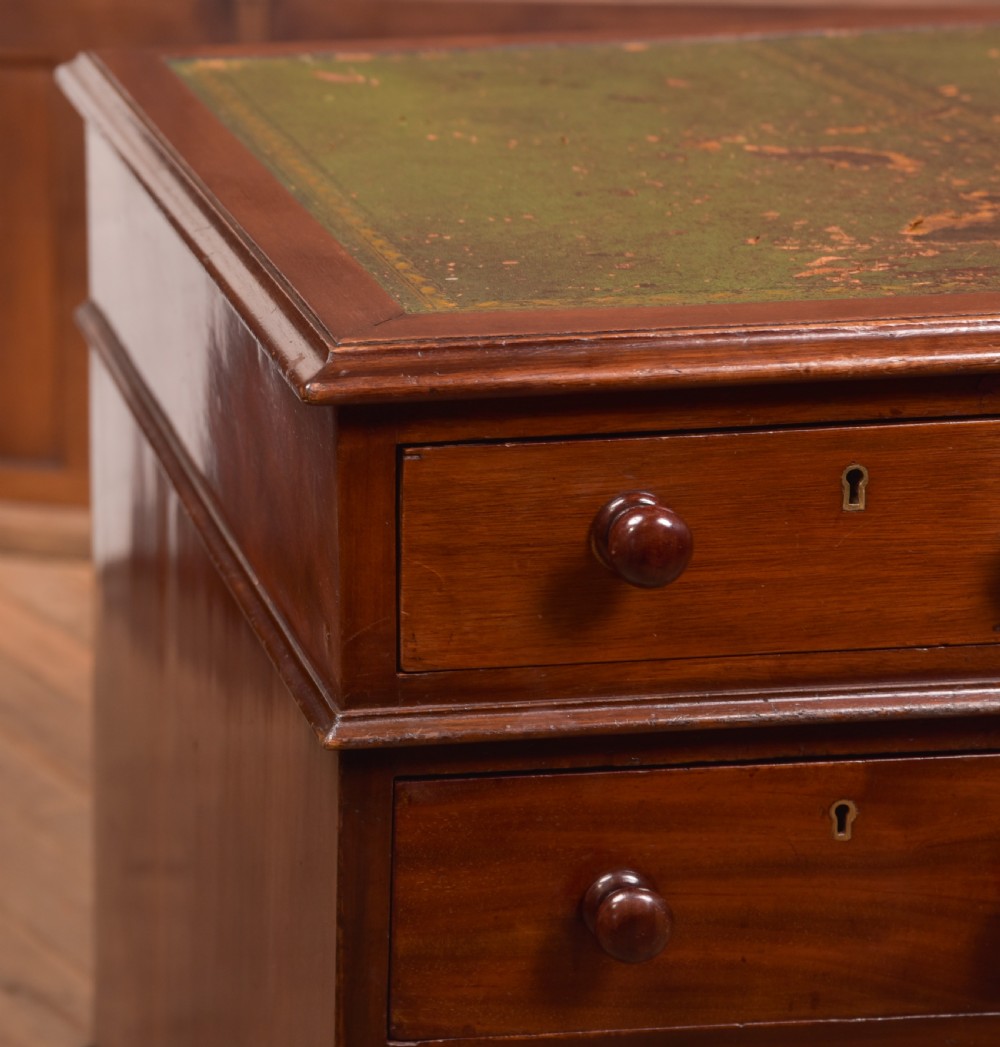 A Victorian mahogany pedestal desk with a green inset leather writing surface, multiple drawers fitted with turned wooden handles, and pedestal bases with bracket feet. View V
