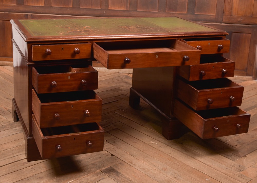 A Victorian mahogany pedestal desk with a green inset leather writing surface, multiple drawers fitted with turned wooden handles, and pedestal bases with bracket feet. View VIII