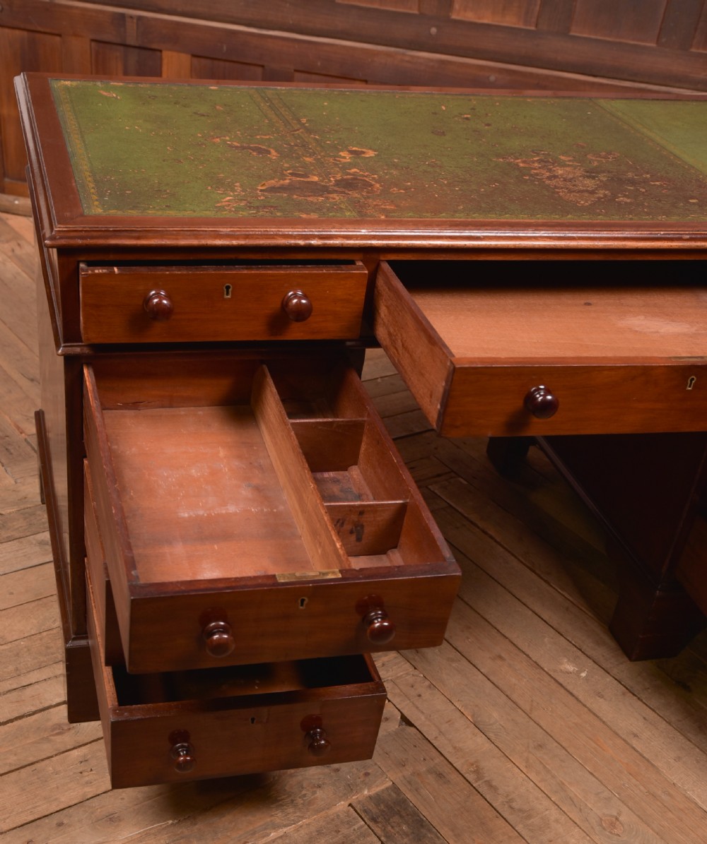 A Victorian mahogany pedestal desk with a green inset leather writing surface, multiple drawers fitted with turned wooden handles, and pedestal bases with bracket feet. View IX
