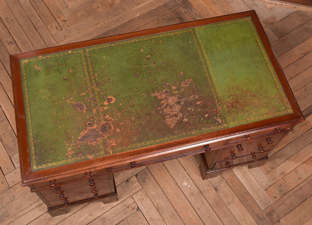 A Victorian mahogany pedestal desk with a green inset leather writing surface, multiple drawers fitted with turned wooden handles, and pedestal bases with bracket feet. View X