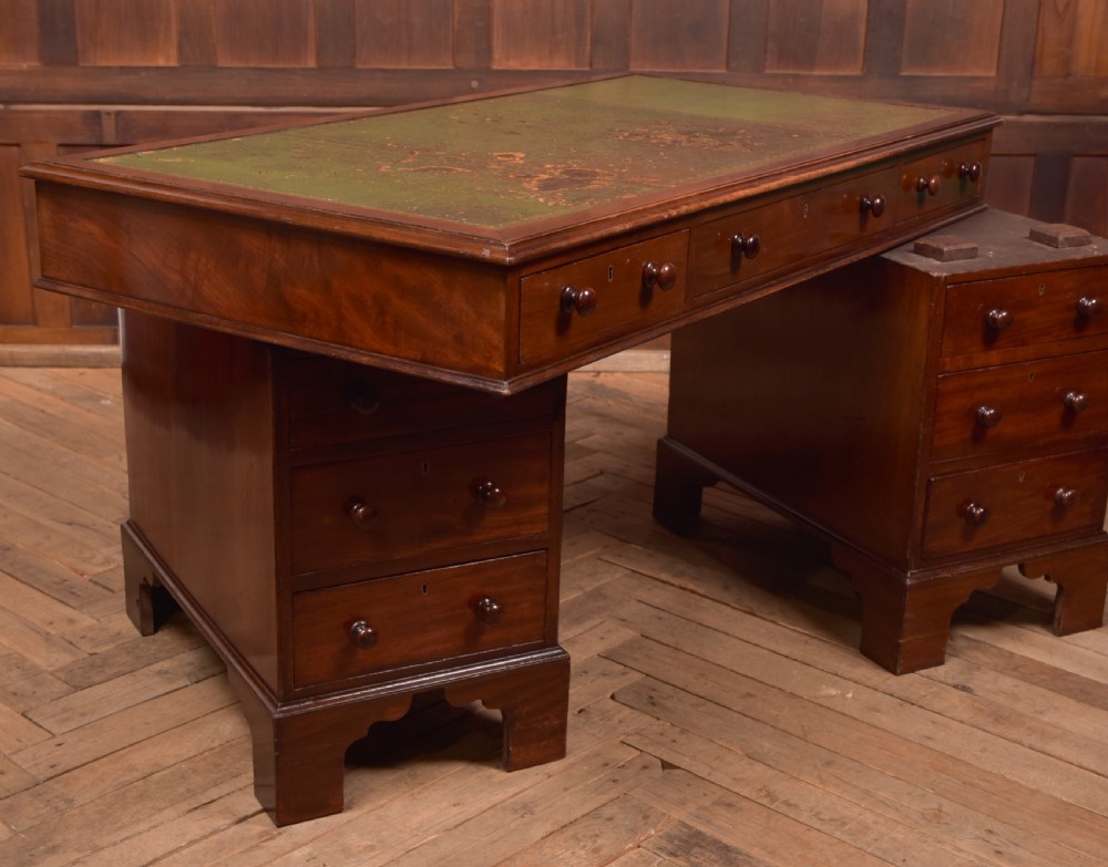 A Victorian mahogany pedestal desk with a green inset leather writing surface, multiple drawers fitted with turned wooden handles, and pedestal bases with bracket feet. View XII