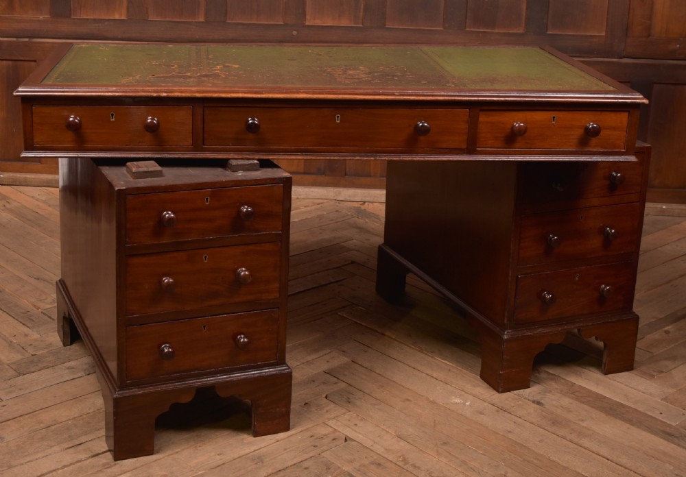 A Victorian mahogany pedestal desk with a green inset leather writing surface, multiple drawers fitted with turned wooden handles, and pedestal bases with bracket feet. View XIV