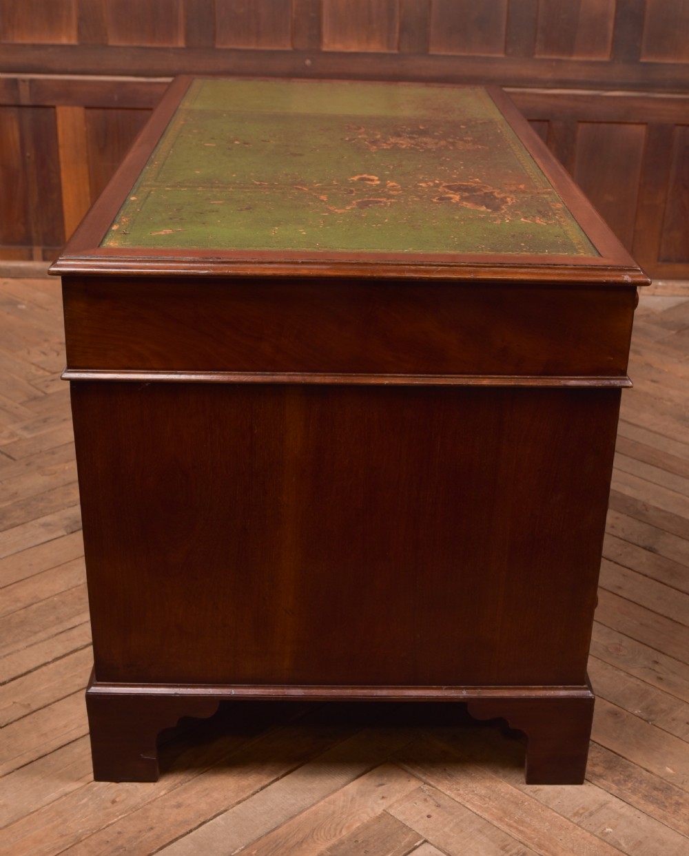 A Victorian mahogany pedestal desk with a green inset leather writing surface, multiple drawers fitted with turned wooden handles, and pedestal bases with bracket feet. View XV