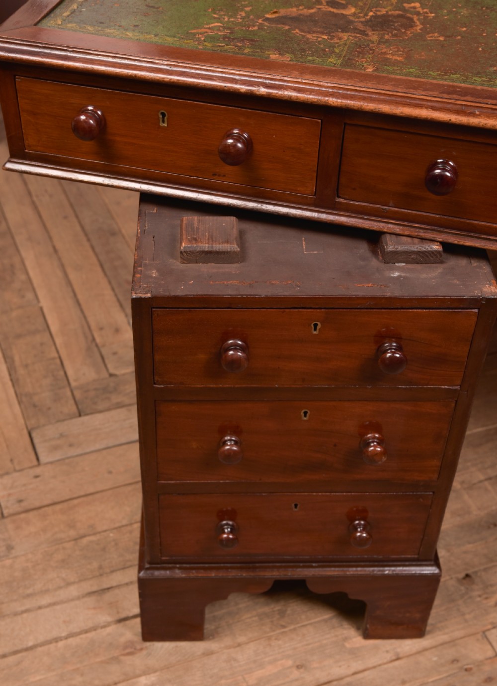 A Victorian mahogany pedestal desk with a green inset leather writing surface, multiple drawers fitted with turned wooden handles, and pedestal bases with bracket feet. View XVI