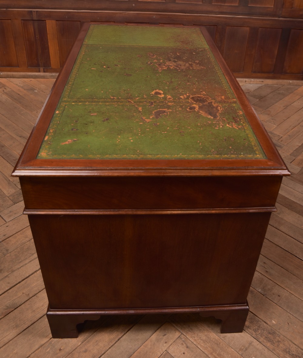 A Victorian mahogany pedestal desk with a green inset leather writing surface, multiple drawers fitted with turned wooden handles, and pedestal bases with bracket feet. View XVII
