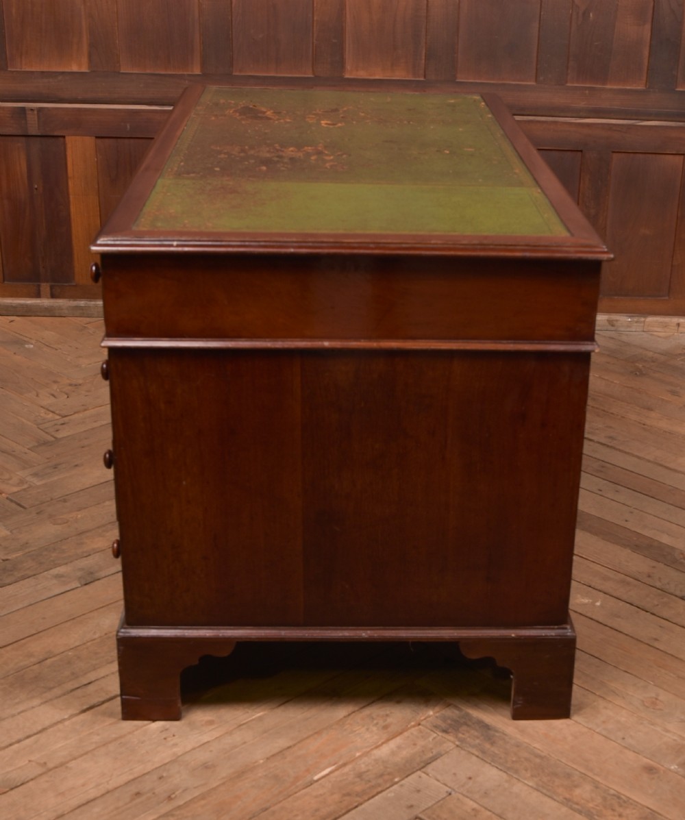 A Victorian mahogany pedestal desk with a green inset leather writing surface, multiple drawers fitted with turned wooden handles, and pedestal bases with bracket feet. View XIX