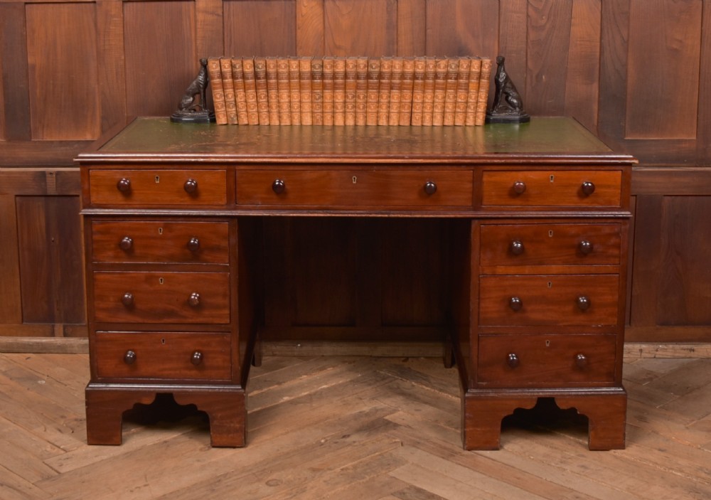 A Victorian mahogany pedestal desk with a green inset leather writing surface, multiple drawers fitted with turned wooden handles, and pedestal bases with bracket feet. View XXI