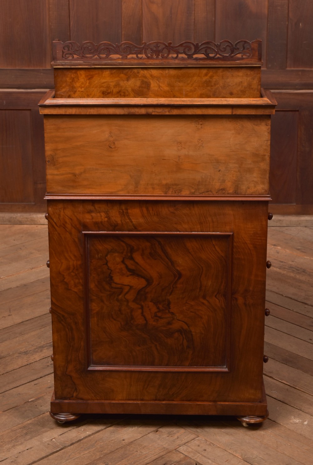 A Victorian burr walnut piano top Davenport desk featuring a carved fretwork gallery, sloped writing lid, scroll front supports, and side-opening drawers. View VIII