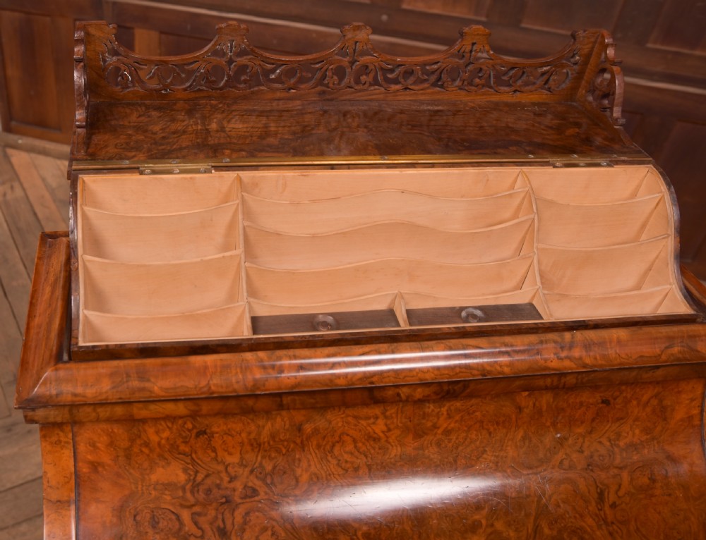 A Victorian burr walnut piano top Davenport desk featuring a carved fretwork gallery, sloped writing lid, scroll front supports, and side-opening drawers. View XIV