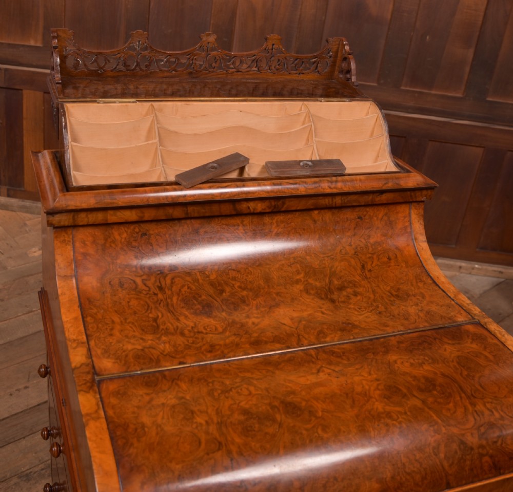 A Victorian burr walnut piano top Davenport desk featuring a carved fretwork gallery, sloped writing lid, scroll front supports, and side-opening drawers. View XV