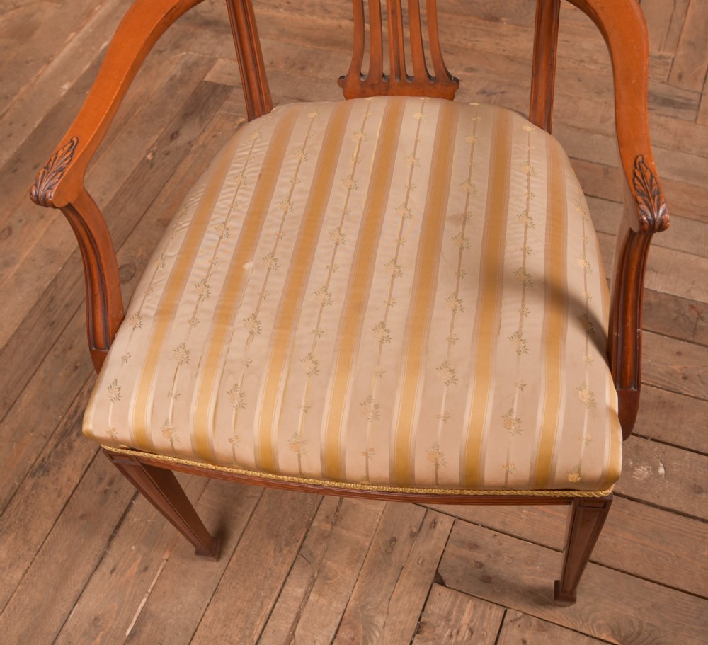 An Edwardian satinwood armchair with a carved pierced splat back, sweeping armrests, and a striped gold upholstered seat. View II