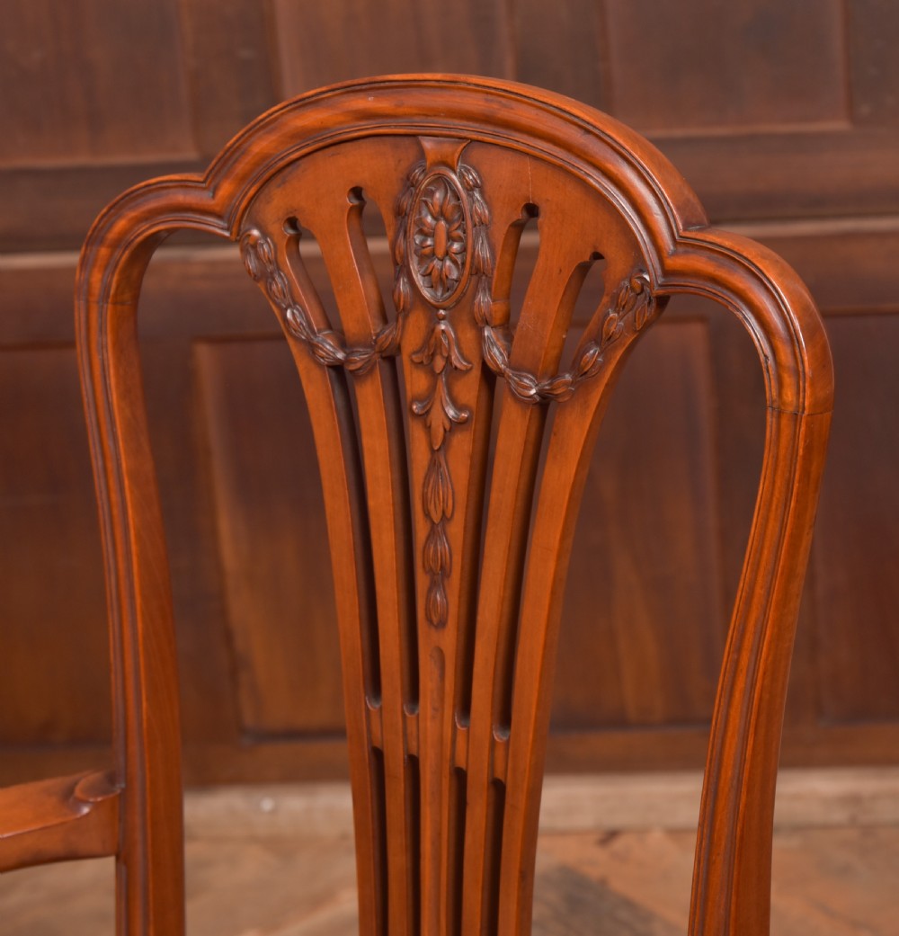 An Edwardian satinwood armchair with a carved pierced splat back, sweeping armrests, and a striped gold upholstered seat. View V