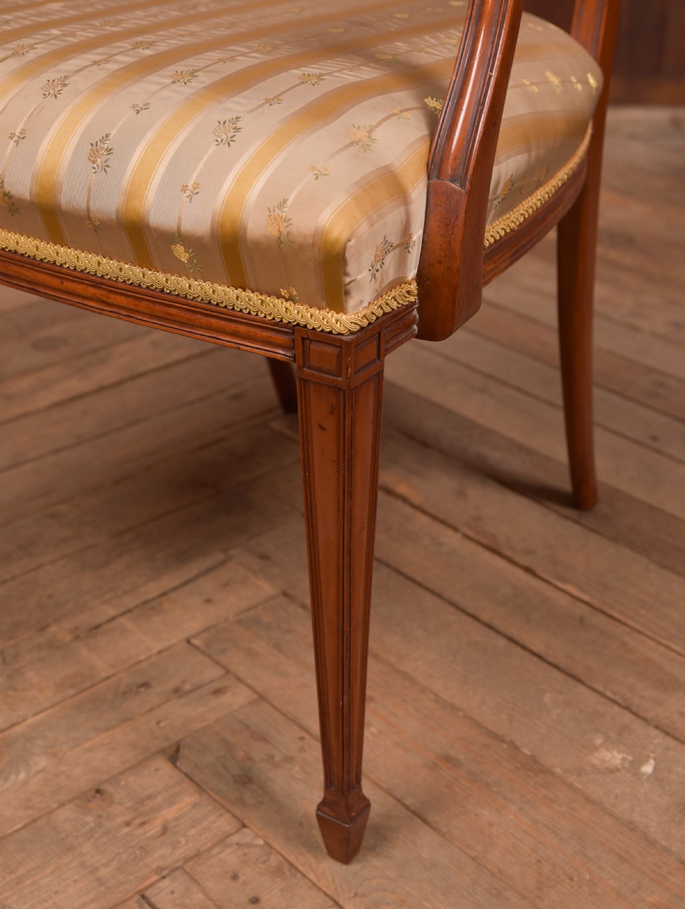 An Edwardian satinwood armchair with a carved pierced splat back, sweeping armrests, and a striped gold upholstered seat. View VI