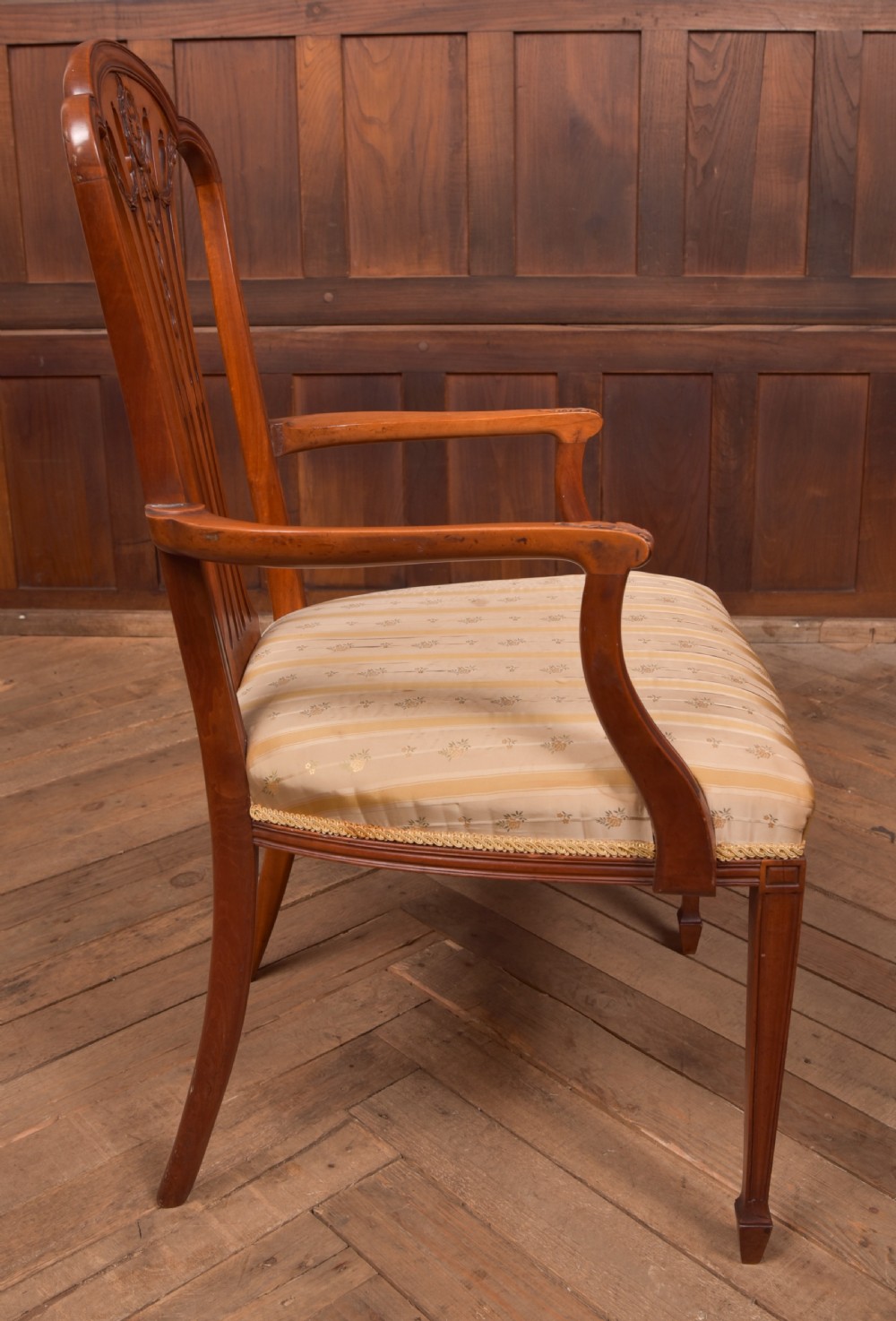 An Edwardian satinwood armchair with a carved pierced splat back, sweeping armrests, and a striped gold upholstered seat. View IX