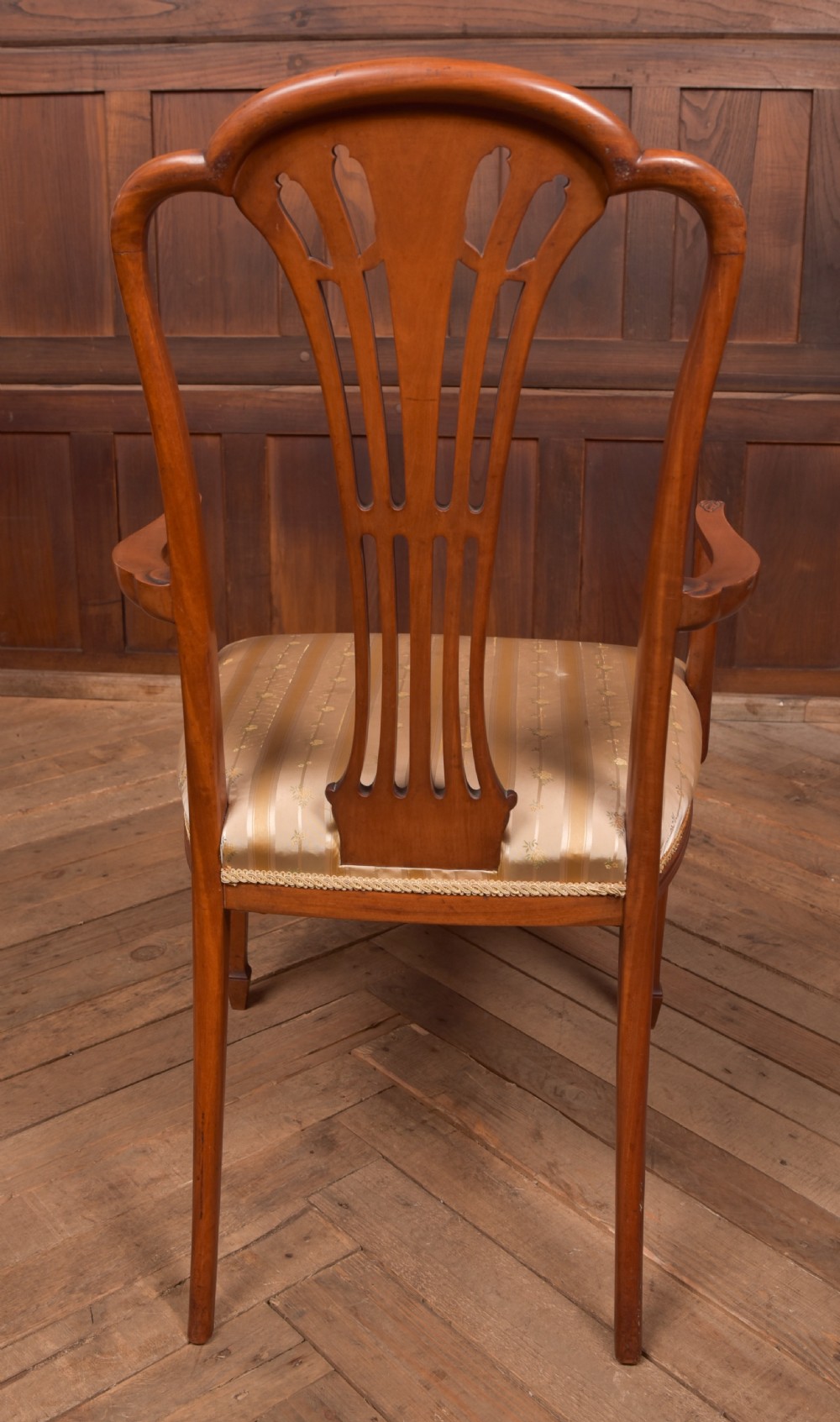 An Edwardian satinwood armchair with a carved pierced splat back, sweeping armrests, and a striped gold upholstered seat. View X