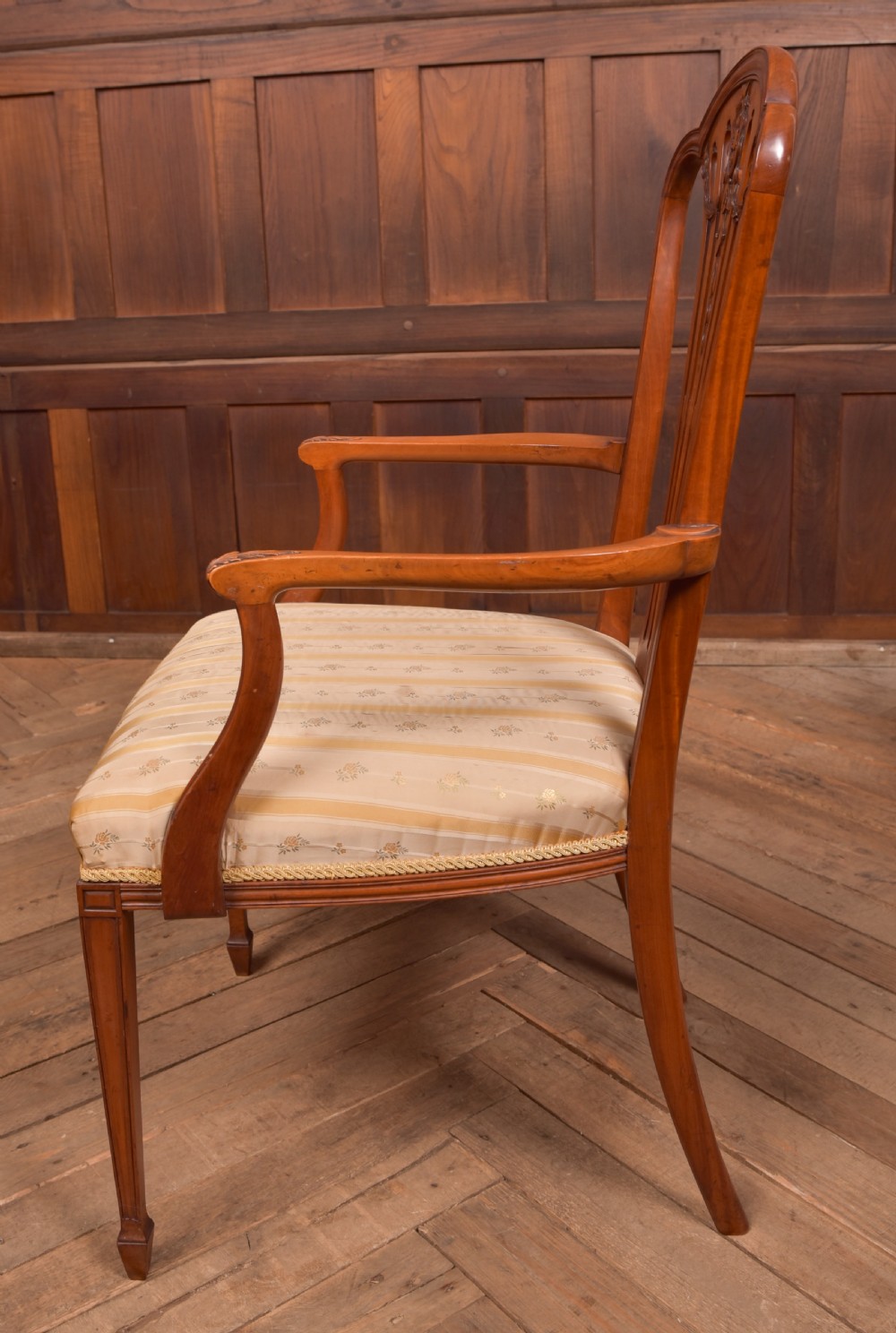 An Edwardian satinwood armchair with a carved pierced splat back, sweeping armrests, and a striped gold upholstered seat. View XI