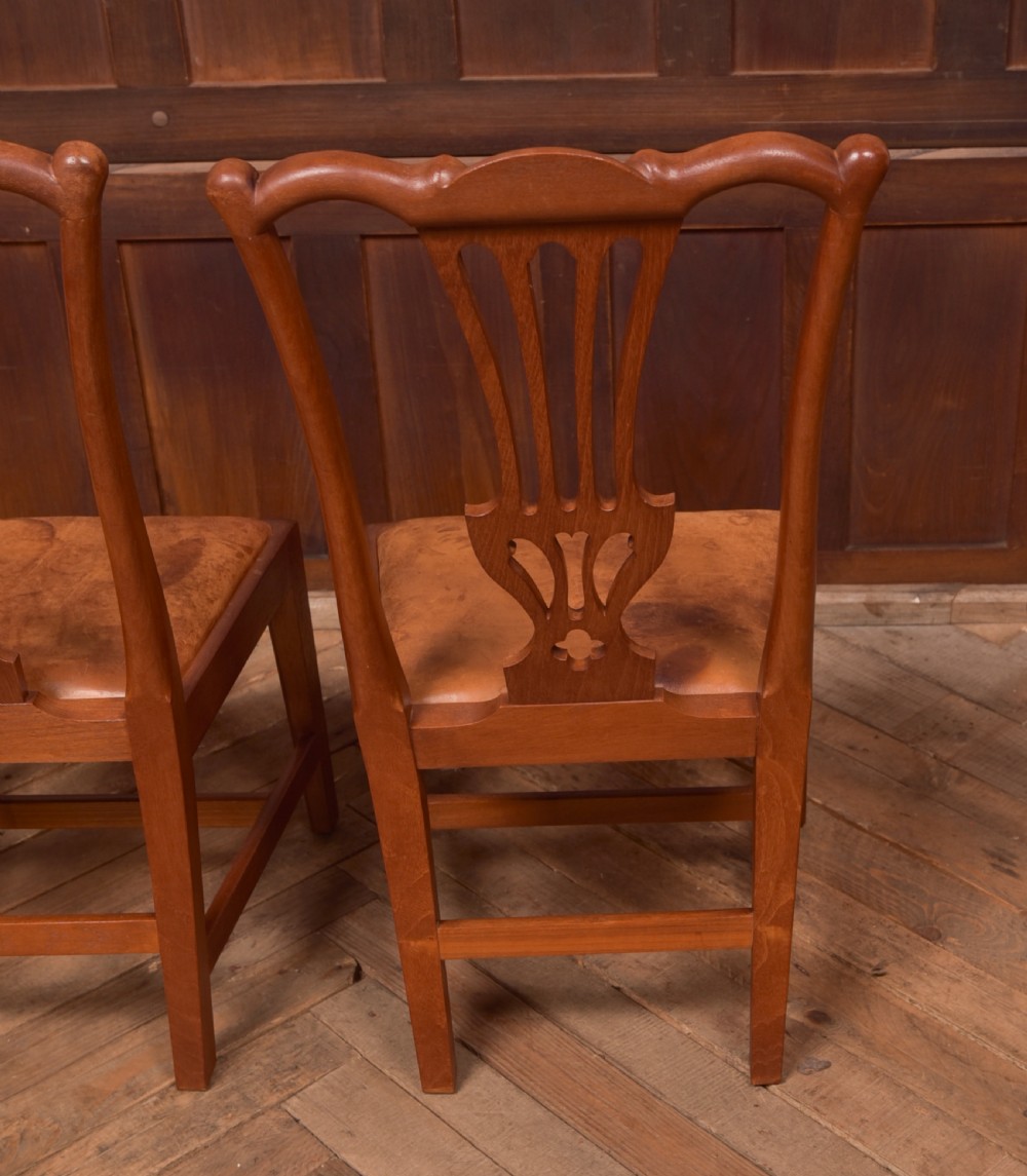 A matching pair of warm brown walnut side chairs with pierced vasiform splats, shaped crest rails, and upholstered drop-in seats supported by square legs with H-stretchers. View V