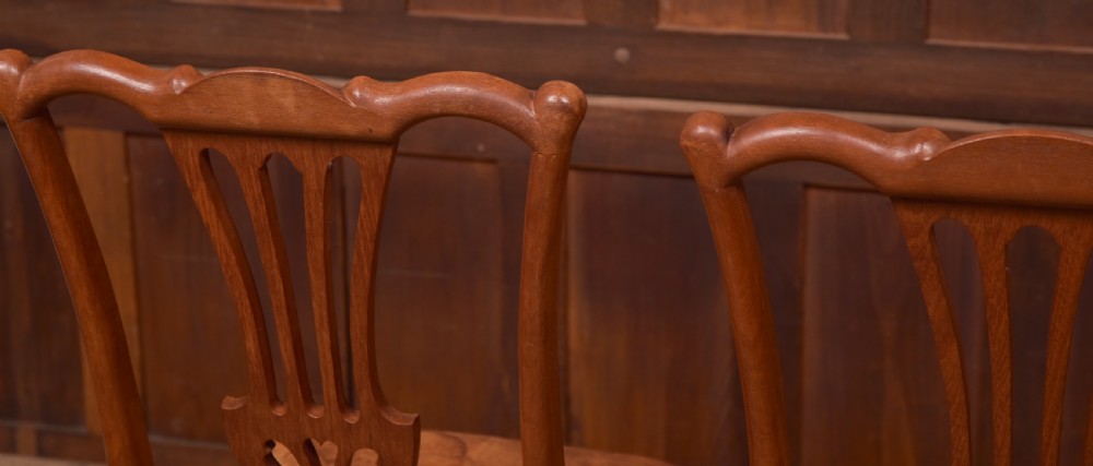 A matching pair of warm brown walnut side chairs with pierced vasiform splats, shaped crest rails, and upholstered drop-in seats supported by square legs with H-stretchers. View VII