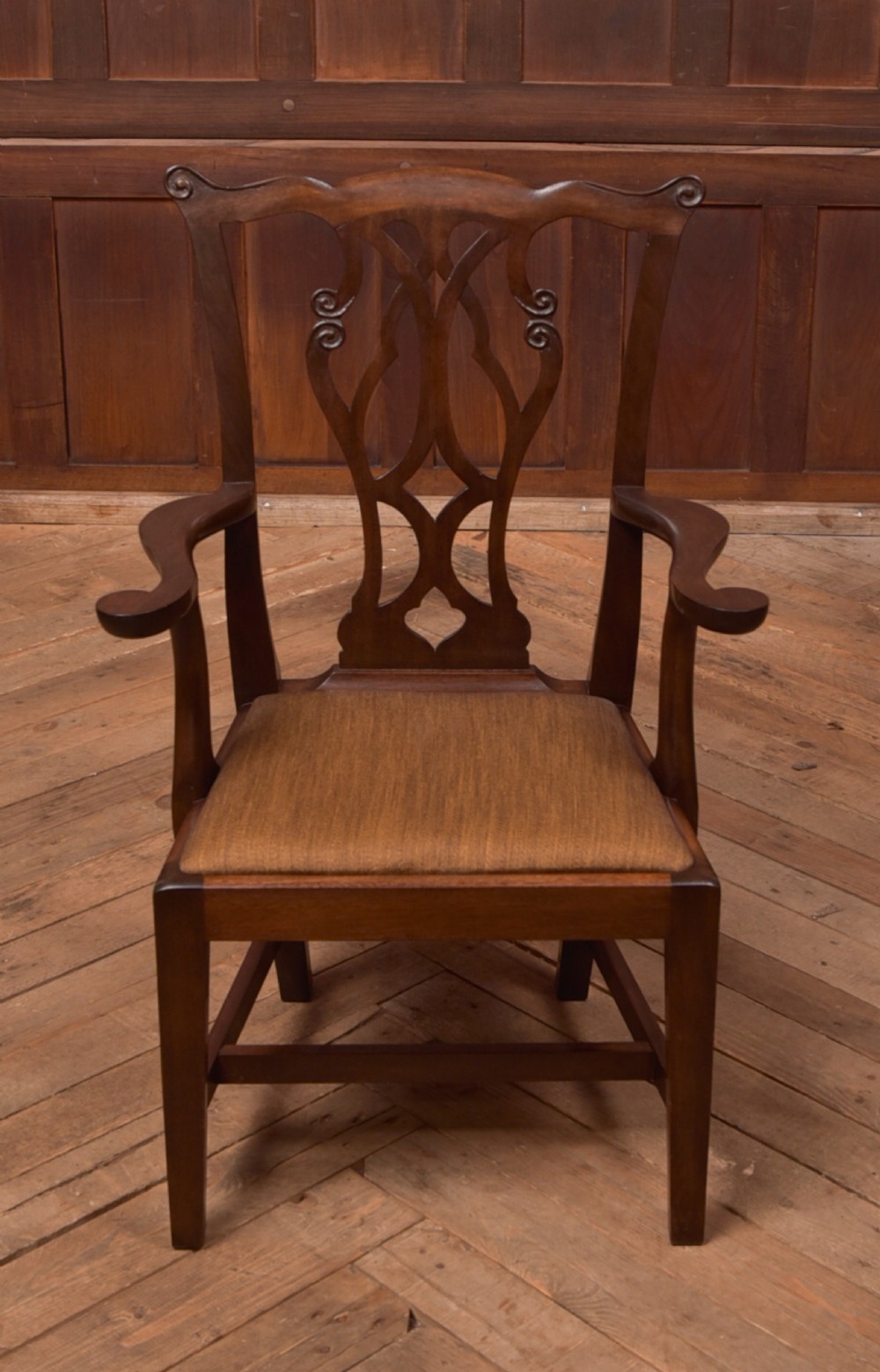 A dark hardwood open armchair featuring a pierced carved back splat, curved armrests, and a textured brown upholstered drop-in seat. View X