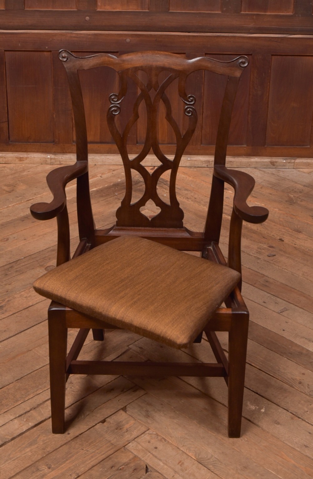 A dark hardwood open armchair featuring a pierced carved back splat, curved armrests, and a textured brown upholstered drop-in seat. View XI