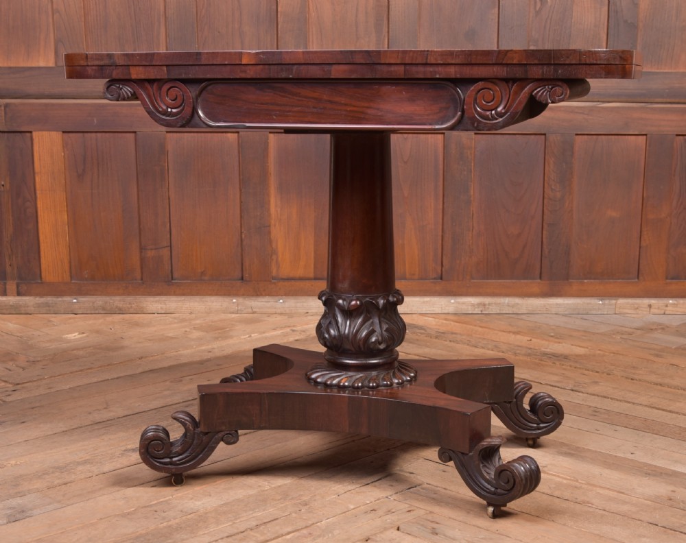 A Victorian rosewood fold-over card table featuring a rectangular swivel top, carved frieze, central column support, and a quadform base with scroll feet. View II