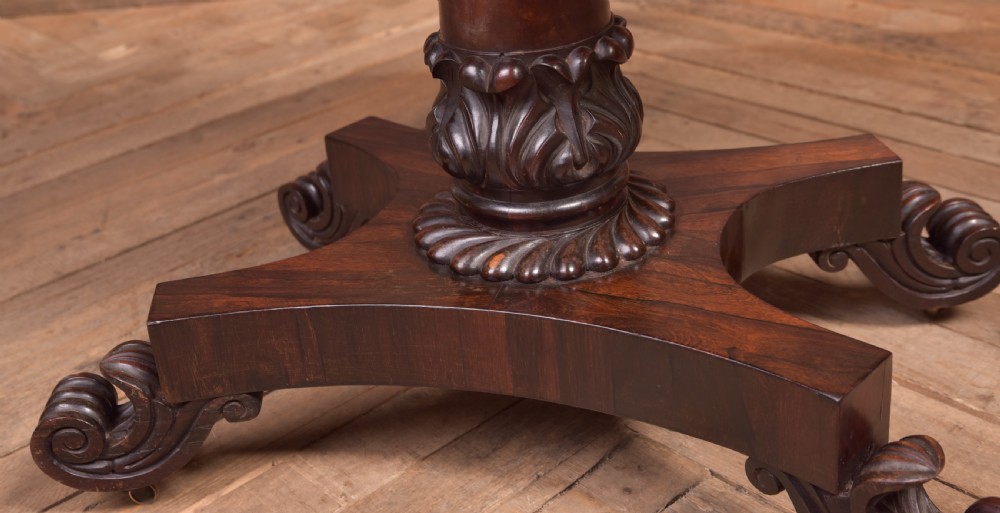 A Victorian rosewood fold-over card table featuring a rectangular swivel top, carved frieze, central column support, and a quadform base with scroll feet. View V
