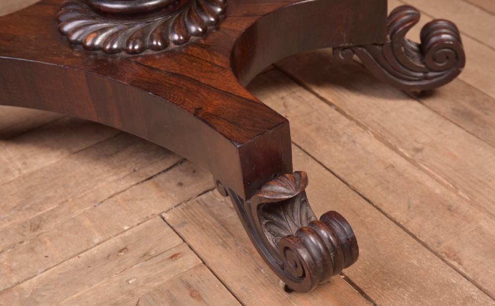 A Victorian rosewood fold-over card table featuring a rectangular swivel top, carved frieze, central column support, and a quadform base with scroll feet. View VIII