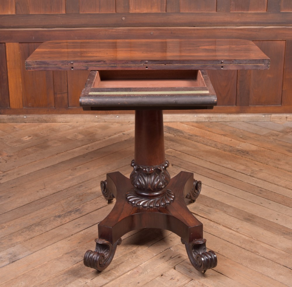 A Victorian rosewood fold-over card table featuring a rectangular swivel top, carved frieze, central column support, and a quadform base with scroll feet. View XI