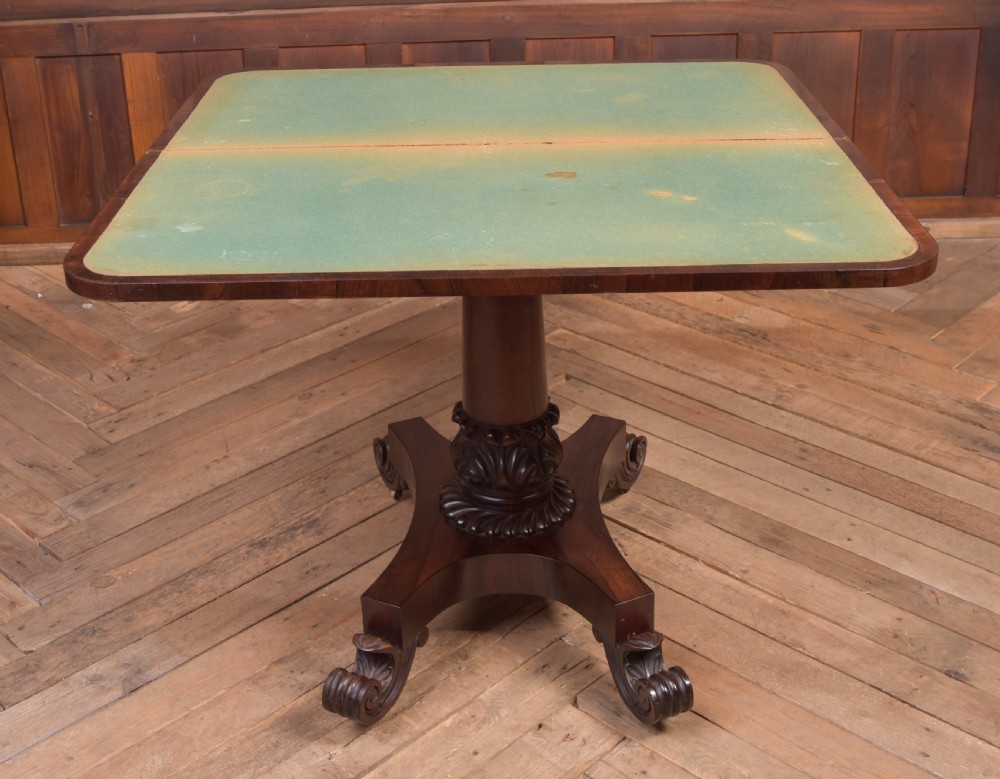 A Victorian rosewood fold-over card table featuring a rectangular swivel top, carved frieze, central column support, and a quadform base with scroll feet. View XII