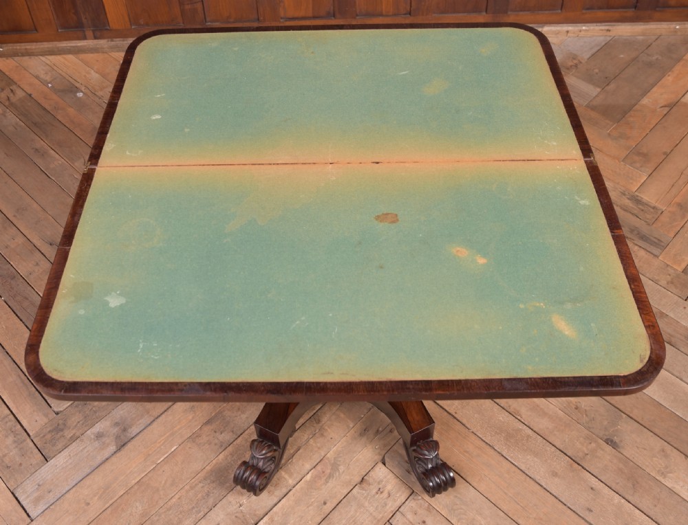 A Victorian rosewood fold-over card table featuring a rectangular swivel top, carved frieze, central column support, and a quadform base with scroll feet. View XIII