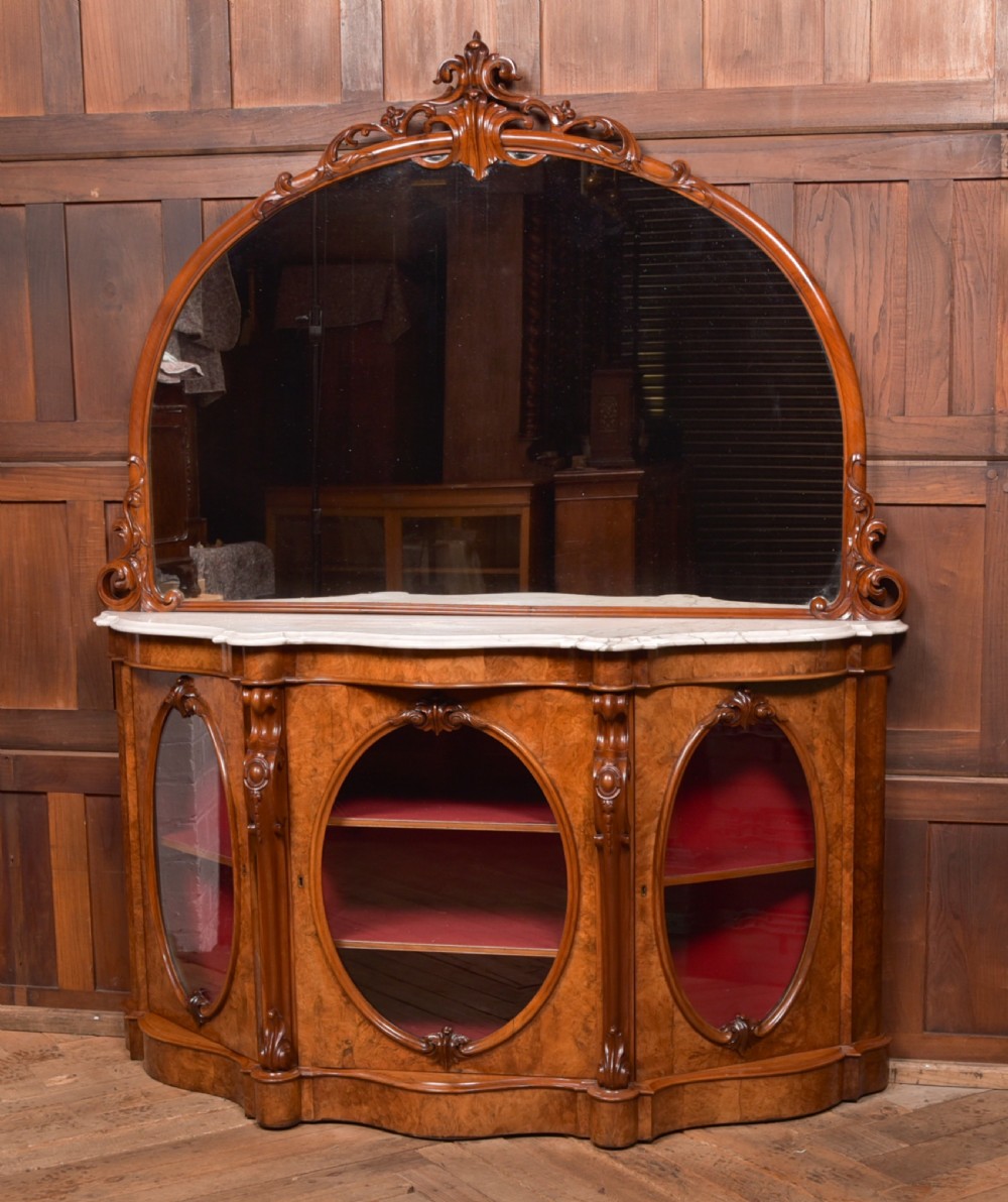 A Victorian burr walnut mirror-back credenza featuring a shaped white marble top, carved scrollwork crest, and three oval glazed cabinet doors revealing red fabric lining. View III