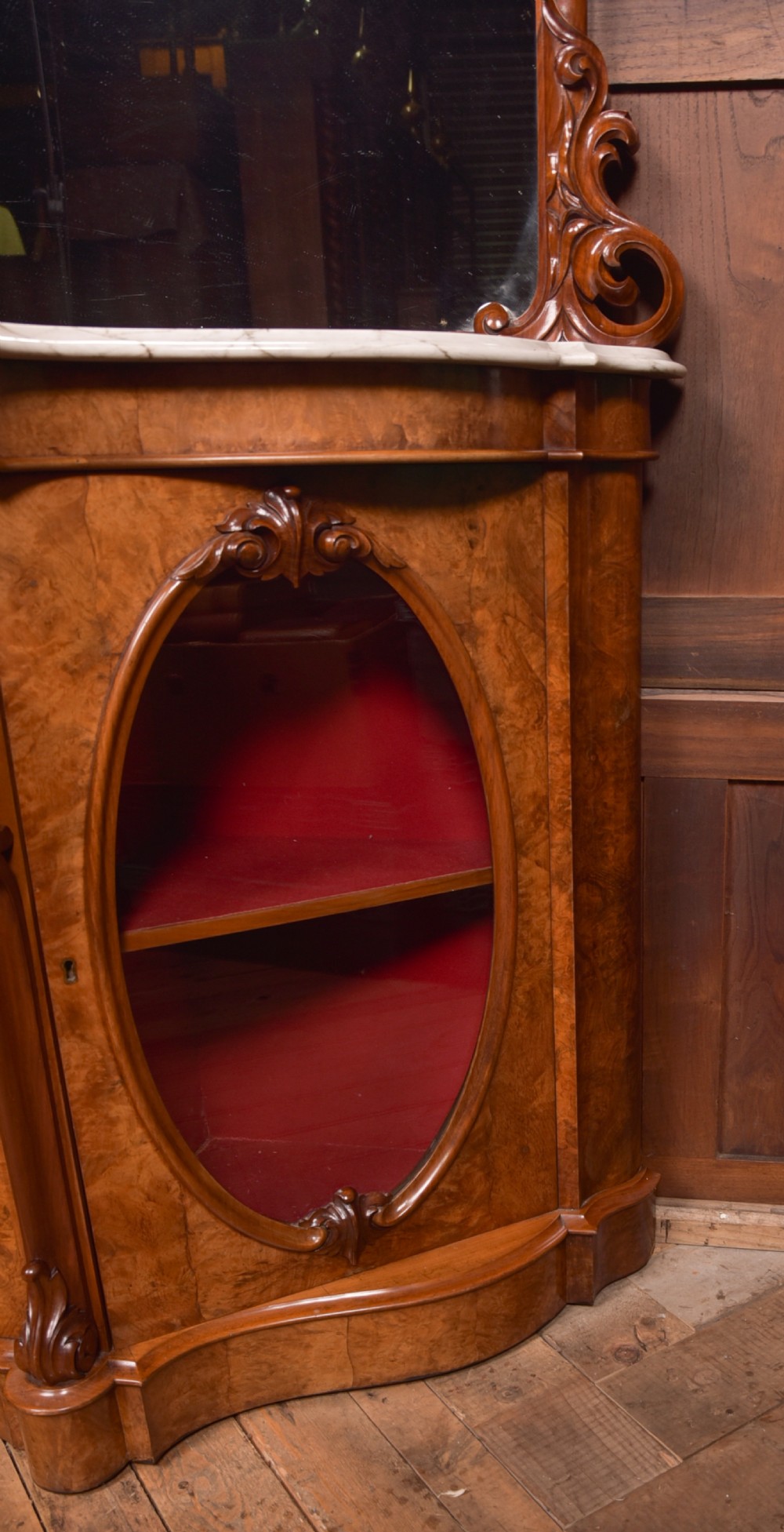 A Victorian burr walnut mirror-back credenza featuring a shaped white marble top, carved scrollwork crest, and three oval glazed cabinet doors revealing red fabric lining. View XI