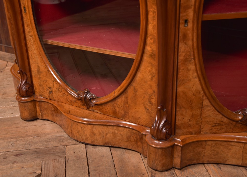 A Victorian burr walnut mirror-back credenza featuring a shaped white marble top, carved scrollwork crest, and three oval glazed cabinet doors revealing red fabric lining. View XII