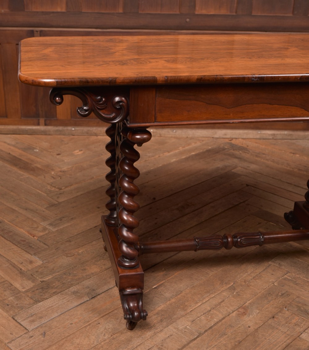 A Victorian wooden side table featuring a rectangular top with rounded corners, carved scroll brackets, double barley twist legs, a central stretcher, and castors. View II