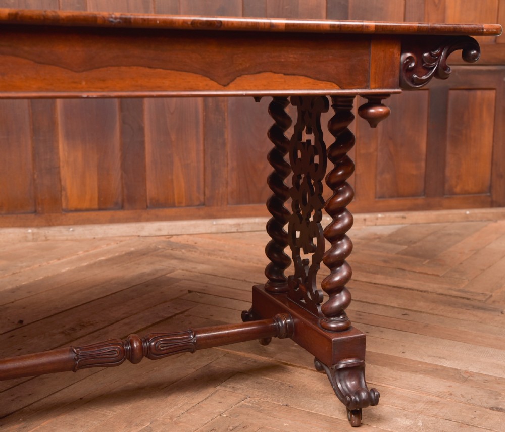 A Victorian wooden side table featuring a rectangular top with rounded corners, carved scroll brackets, double barley twist legs, a central stretcher, and castors. View V