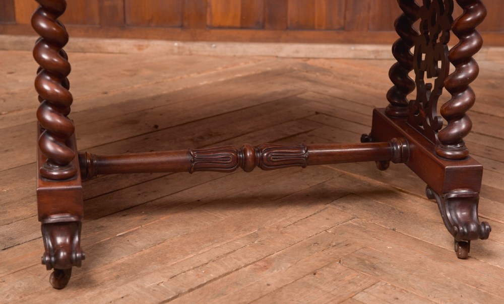 A Victorian wooden side table featuring a rectangular top with rounded corners, carved scroll brackets, double barley twist legs, a central stretcher, and castors. View VII