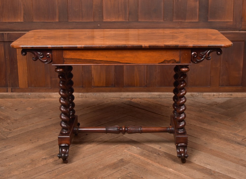 A Victorian wooden side table featuring a rectangular top with rounded corners, carved scroll brackets, double barley twist legs, a central stretcher, and castors. View X