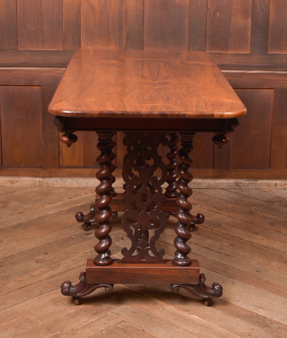 A Victorian wooden side table featuring a rectangular top with rounded corners, carved scroll brackets, double barley twist legs, a central stretcher, and castors. View XI