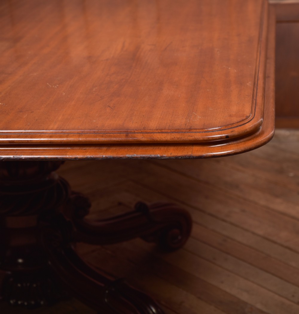 A Victorian mahogany tilt-top table featuring a polished rectangular top with rounded corners set upon a carved pedestal stem with quadruped scrolled legs. View III
