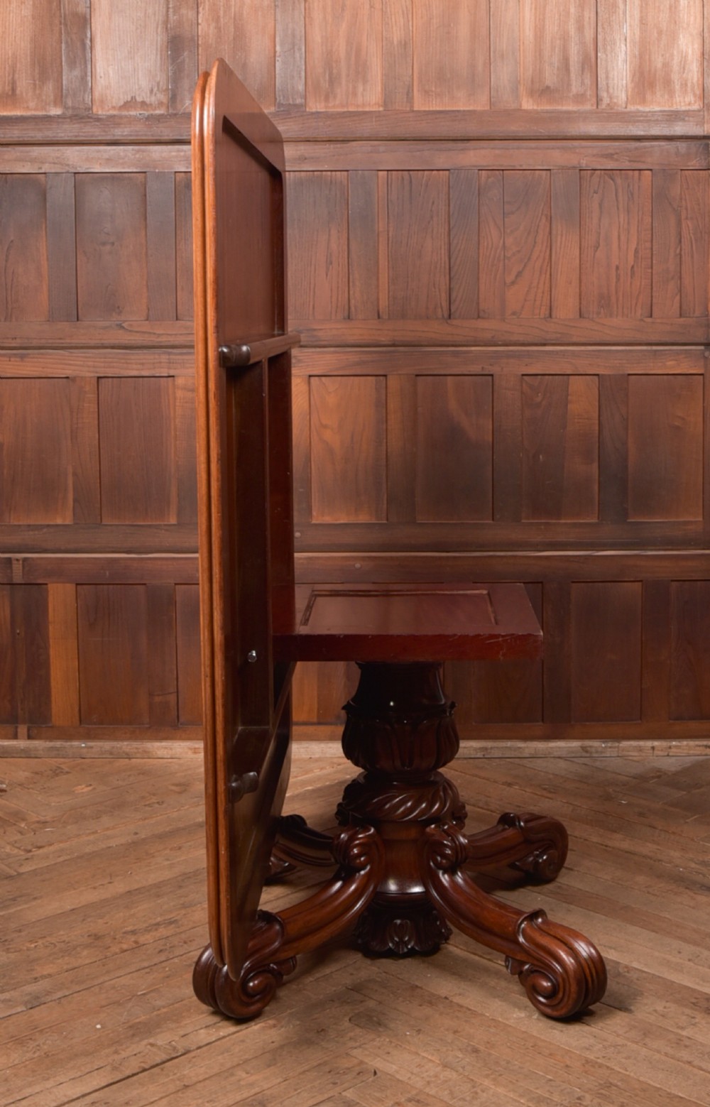 A Victorian mahogany tilt-top table featuring a polished rectangular top with rounded corners set upon a carved pedestal stem with quadruped scrolled legs. View VII